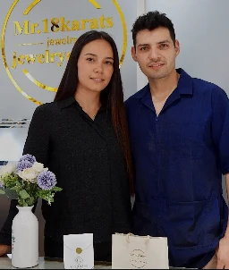 Jhonatan Polanco Galindo junto a su compañera en el local de la joyería en Pitalito, frente al logo de la marca